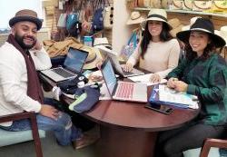三个戴着帽子的学生坐在桌边讨论时装销售
